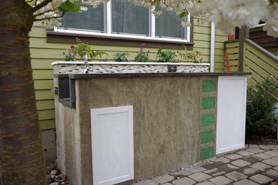 The nearly complete shed, missing only door handles.  The flower bed drains to the left and highlights the main living room window of the house.